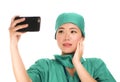 Asian Chinese woman as successful taking selfie on hand phone - young beautiful and happy medicine doctor or hospital nurse taking Royalty Free Stock Photo