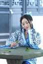 Asian Chinese woman in traditional Blue and white Hanfu dress, kill time in a famous garden