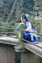 Asian Chinese woman in traditional Blue and white Hanfu dress, play in a famous garden Climb on the bent bridge Royalty Free Stock Photo