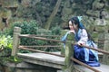 Asian Chinese woman in traditional Blue and white Hanfu dress, play in a famous garden Climb on the bent bridge Royalty Free Stock Photo