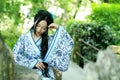 Asian Chinese woman in traditional Blue and white Hanfu dress, play in a famous garden ,sit on an ancient stone chair