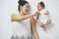 Asian chinese woman mother lying next to newborn child and playing Royalty Free Stock Photo