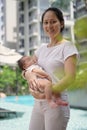 Asian chinese young mother carrying newborn child at her home swimming pool Royalty Free Stock Photo