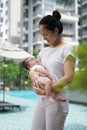 Asian chinese young mother carrying newborn child at her home swimming pool Royalty Free Stock Photo