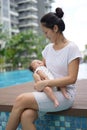 Asian chinese young mother carrying newborn child at her home swimming pool Royalty Free Stock Photo