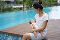 Asian chinese young mother looking at newborn child at her home swimming pool Royalty Free Stock Photo