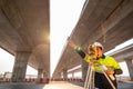 Asian civil engineer or surveyor making measuring and pointing finger under the expressway with theodolite on road works. Survey Royalty Free Stock Photo