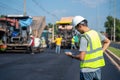 Asian civil engineer working on a road construction site with Asphalt paver & road roller & dump truck and worker construction Royalty Free Stock Photo