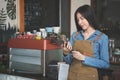 Asian Coffee Shop Owner Accepts a Pre-Order on a Tablet Smiling to the Customer in a Cozy Cafe. Restaurant Manager Browsing Royalty Free Stock Photo