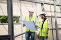 Asian Colleagues worker Specialists team wearing protective safety helmet look at blueprint on Construction Site. Civil Engineer M Royalty Free Stock Photo