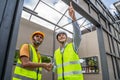 Asian Colleagues worker Specialists team wearing protective safety helmet look at blueprint on Construction Site. Civil Engineer M