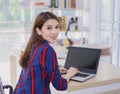 Asian confident female is resting her hand on the keyboard of laptop and turn back her face with smiling in a working room at home Royalty Free Stock Photo