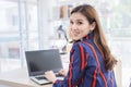 Asian confident woman is resting her hand on the keyboard of laptop and turn back her face with smiling in a working room Royalty Free Stock Photo