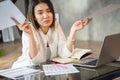 Asian confused woman working with papers and laptop