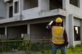 Asian construction site manager wearing safety vest and helmet thinking at architect construction Royalty Free Stock Photo