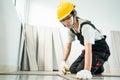 Asian Construction woman worker Joiner work in site to renovate home. Female craftsman wearing jumpsuit, safety yellow helmet and