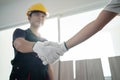 Asian Construction worker greeting by handshake with builder at home. Craftsman people wear yellow helmet, talk with Carpenter in