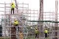 asian construction workers working on scaffolding of building construction site in city. urban expansion in capital city of asia