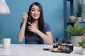 Asian content creator using brush while doing makeup tutorial at camera