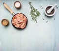 Asian cooking ingredients with fresh small shrimp in a small frying pan, herbs and pepper wood blue background top view border,