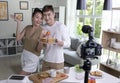 Asian couple blogger influencer vlogger shooting video in kitchen. Young couple live-streaming cooking class from home. Royalty Free Stock Photo
