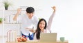 Asian couple celebrating their sale after using computer laptop for online auction while working from home for new normal policy Royalty Free Stock Photo