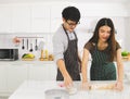 Asian couple cooking pizza in modern kitchen, cutting a pizza and smiling together Royalty Free Stock Photo