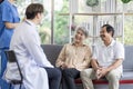 Asian couple Elderly men and women sit on sofas having fun and having fun talking with doctors who come to check their health at Royalty Free Stock Photo