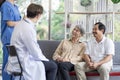 Asian couple Elderly men and women sit on sofas having fun and having fun talking with doctors who come to check their health at Royalty Free Stock Photo