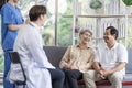 Asian couple Elderly men and women sit on sofas having fun and having fun talking with doctors who come to check their health at Royalty Free Stock Photo
