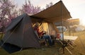 Asian couple enjoy in they tent in camping trip on night time with table, cup, mug and party inside tent, they enjoy coffee Royalty Free Stock Photo