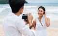 Asian couple enjoying beach vacation holiday. Boyfriend photographer taking a picture of his girlfriend by seaside in Royalty Free Stock Photo