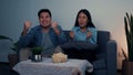 Asian couple has fun cheering on the soccer team competing on TV