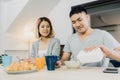 Asian couple having breakfast, cereal in milk, bread and drinking orange juice after wake up in the morning. Royalty Free Stock Photo
