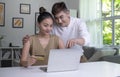 Asian couple holding credit card and using laptop computer. Happy man and woman working at home. Online shopping, e-commerce Royalty Free Stock Photo