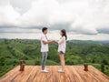 Asian couple holding hands on wooden balcony with mountain view. Mariage proposal concept. terrace for camping tent with landscape Royalty Free Stock Photo