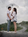 Asian couple holding umbrella on extremely curved road in mountain. Nan, Thailand. sky road on hill. Royalty Free Stock Photo