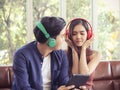 Asian couple listening to music wearing headphones on the couch at home Royalty Free Stock Photo