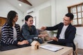 Asian couple looking at house plans and talking with a real estate agent about signing documents for purchase of a new Royalty Free Stock Photo