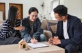 Asian couple looking at house plans and talking with a real estate agent about signing documents for purchase of a new Royalty Free Stock Photo