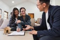 Asian couple looking at house plans and talking with a real estate agent about signing documents for purchase of a new Royalty Free Stock Photo