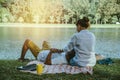 Asian couple lover sitting a relax River side in the public park. working with a notebook and drinking coffee.in the park. in the