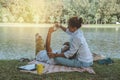 Asian couple lover sitting a relax River side in the public park. working with a notebook and drinking coffee.in the park. in the