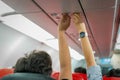 Asian couple people cabin crew, hand up to adjust console panel; the air condition, light / lamp above the low cost airline seat