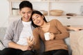 Asian couple resting on couch, using phone