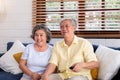 Asian couple senior sitting on sofa and use remote control to change channel and watching tv in living room at home Royalty Free Stock Photo