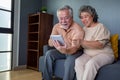 Asian couple of seniors smiling and looking at the same tablet on the sofa at home Royalty Free Stock Photo