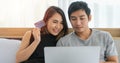 Asian Couple shopping online and paying with credit card at laptop computer,Happy couple at home surfing the net in bed Royalty Free Stock Photo