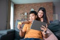 Asian Couple shopping online and paying with credit card at laptop computer,Happy couple at home surfing the net on sofa Royalty Free Stock Photo