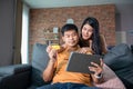 Asian Couple shopping online and paying with credit card at laptop computer,Happy couple at home surfing the net on sofa Royalty Free Stock Photo